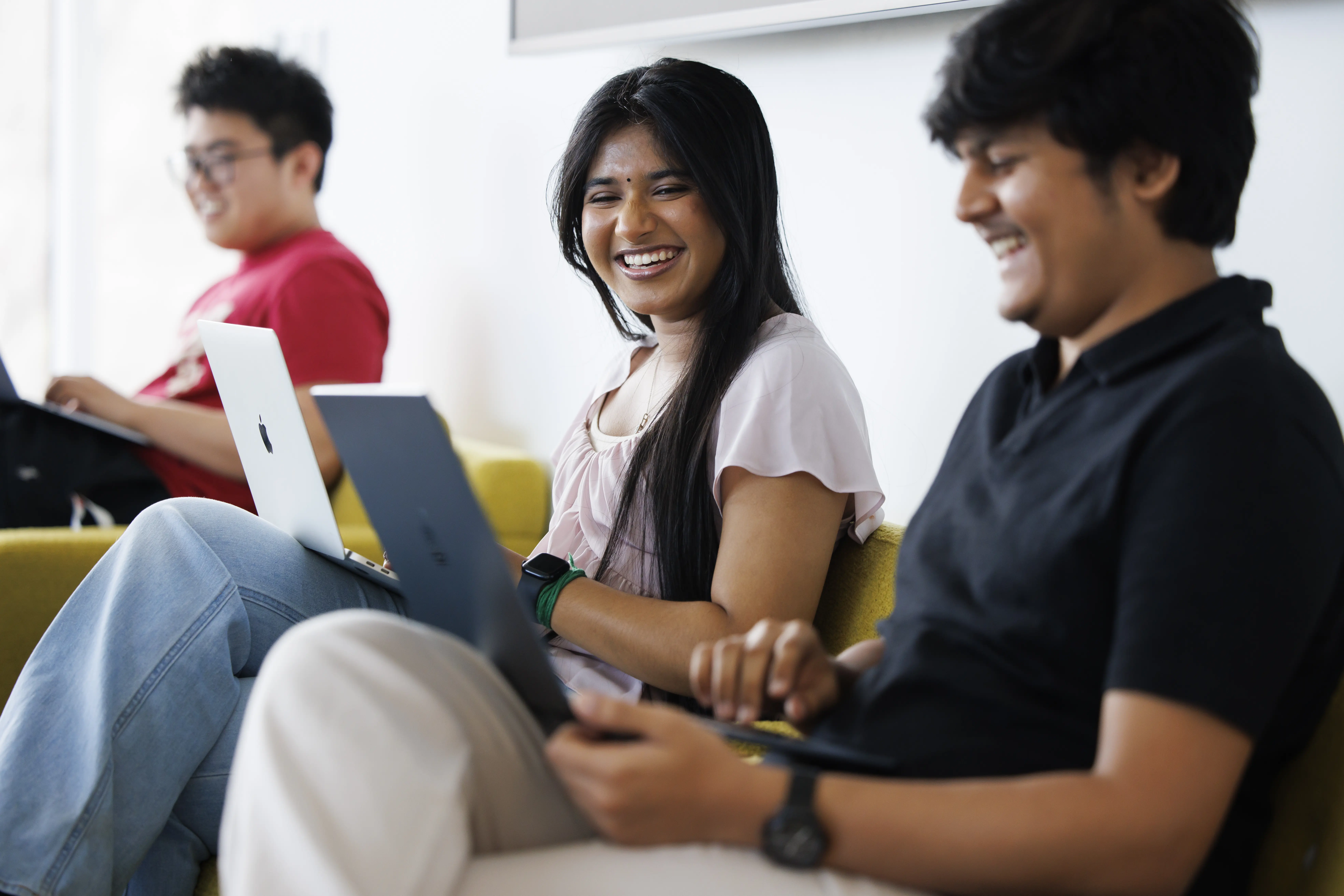 Students smile while working at laptops