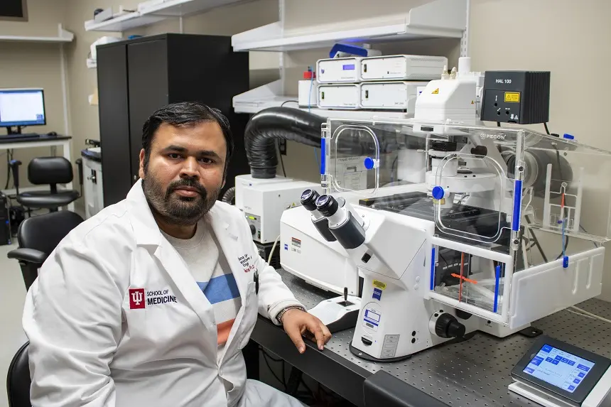 Kanhaiya Singh, PhD, sits at a microscope in the lab