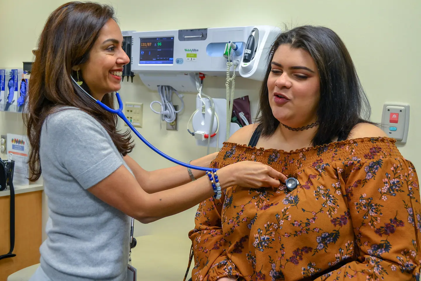 Doctor using a stethoscope on a female patient in a clinic setting