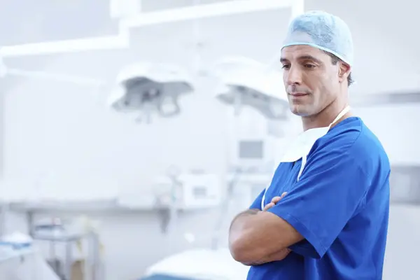 a doctor with a mask around his neck looks somewhat dejected