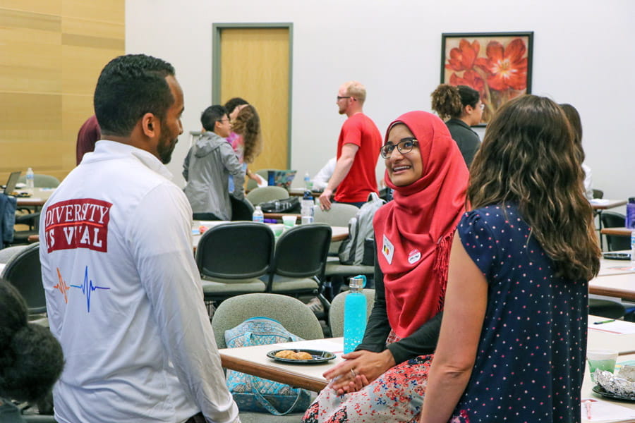 a student wearing a hijab speaks with a faculty member and colleague
