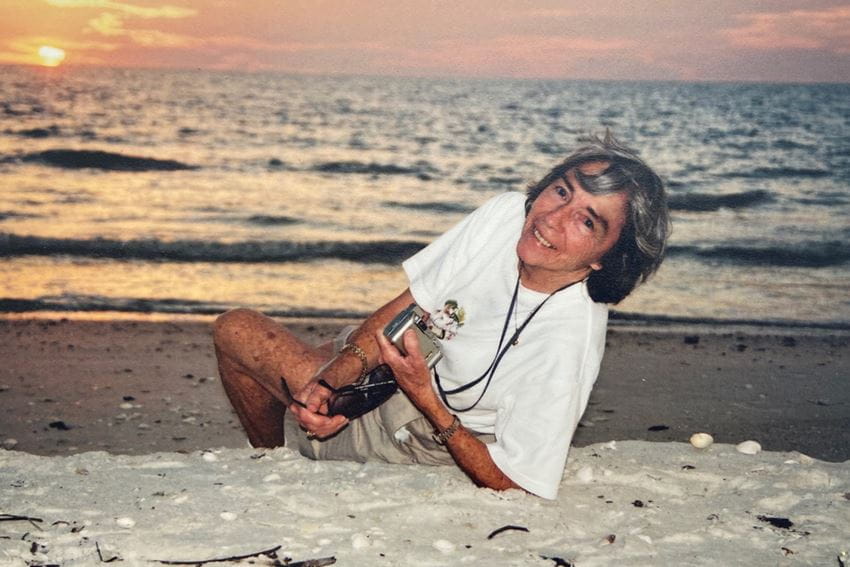 Sarah Roush smiles in an old photograph with the sun setting over a lake in the background