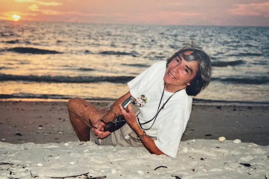 Sarah Roush smiles in an old photograph with the sun setting over a lake in the background