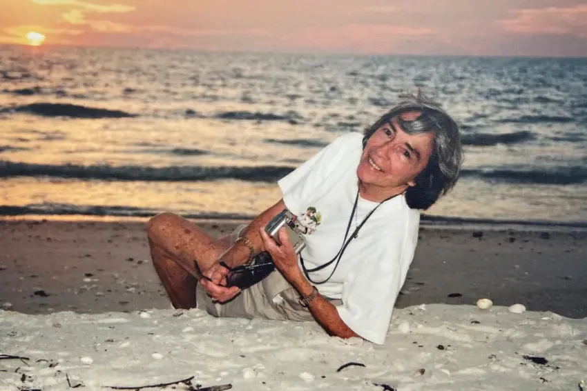 Sarah Roush smiles in an old photograph with the sun setting over a lake in the background