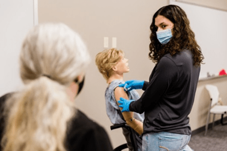 Student learning to give a shot in a mannequin for COVID-19 vaccine distribution
