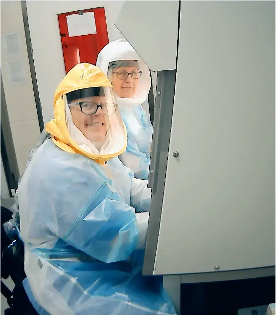 Melissa Kacena and another researcher work while wearing protective coverall suits.