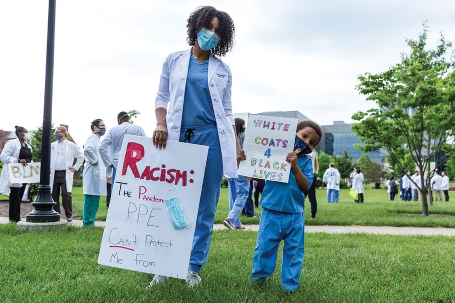 a mother and son, both wearing scrubs, hold protest signs at the White Coats for Black Lives rally in Indianapolis