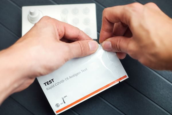 hands opening a COVID 19 rapid test kit