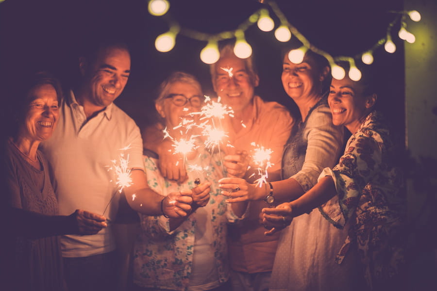 a group of caucasian people with different ages celebrate new years eve with sparklers