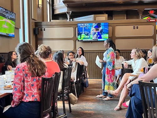 Dr. Francesca Duncan stands in the center of a seated group of women faculty and trainees. 