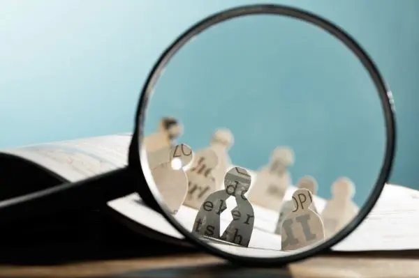 graphic depicting magnifying glass looking at cutouts of people on a blue background