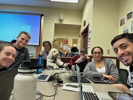 Kennedy and Aura sit at the head of a table surrounded by medical school classmates.