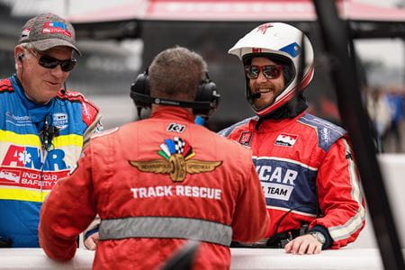 Leonard Edwards talks with two other safety team members, all in fire suits, on Pit Row