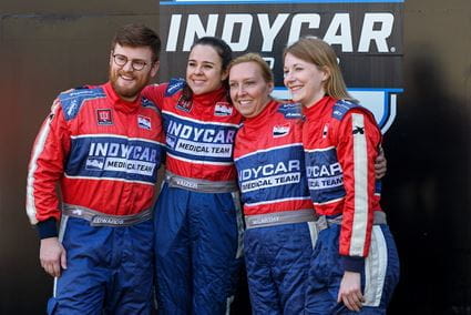 Leonard Edwards, Julia Vaizer, Melissa McCarthy and Liz Sullivan in their IndyCar Medical Team fire suits, posing for a photo at the Indianapolis Motor Speedway