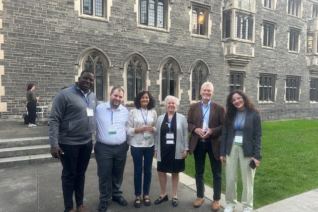 A group of researchers stands together outside a beautiful building