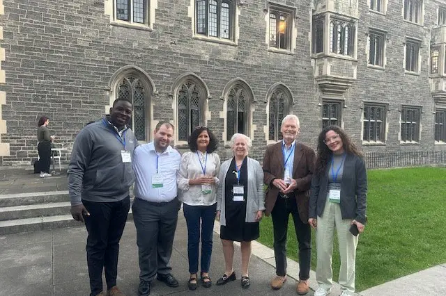 A group of researchers stands together outside a beautiful building