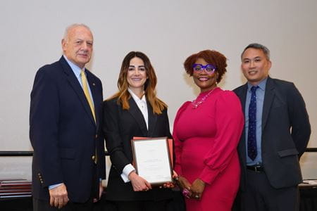 Zeina Nabhan, in suit, holds the ACGME diversity award and poses with two men and one woman representing ACGME.