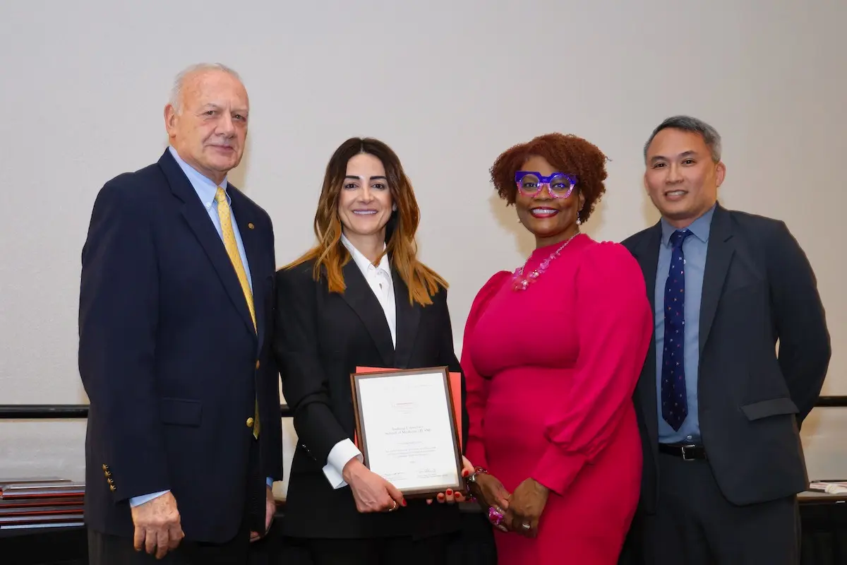 Zeina Nabhan, in suit, holds the ACGME diversity award and poses with two men and one woman representing ACGME.