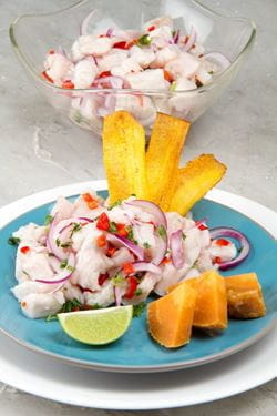 Peruvian ceviche in a dish on a blue plate with lime and sweet potatoes