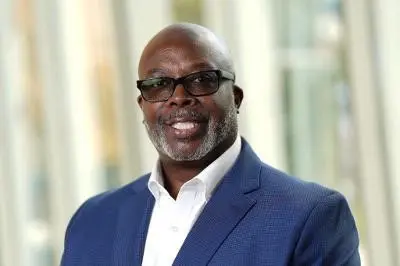 Headshot of Demetrius Logwood, black man with glasses wearing navy suit coat 