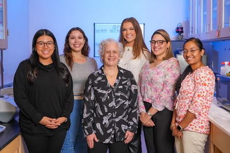 Lilian Plotkin in her lab surrounded by five young women who work in her lab at IU School of Medicine