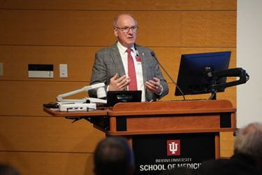 Dean Hess, in suit and tie, speaking behind a podium