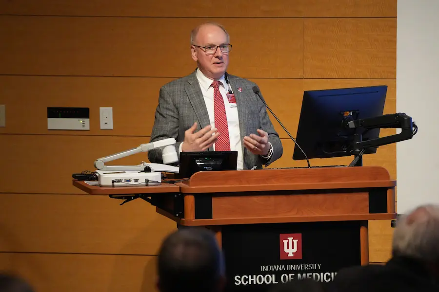 Dean Hess, in suit and tie, speaking behind a podium