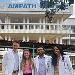 Four medical students stand in front of the AMPATH Centre in Kenya