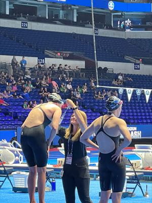 Athletic trainer Katie Keller, a former IU swimmer, awards a medal at the Stadium Splash. She is part of the medical team for the Olympic Trials, led by Stephen Hartsock, MD. Athletic trainer Katie Keller awards a medal to a swimmer on the podium at the Stadium Splash in Lucas Oil Stadium