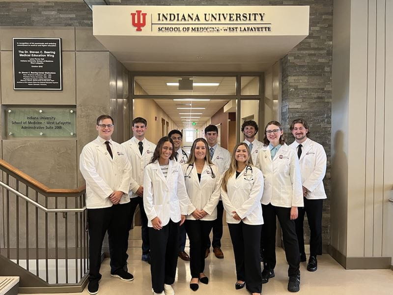Sarah Vaught and classmates in their white coats at IU School of Medicine--West Lafayette 10 students stand in white coats inside the halls of IU School of Medicine-West Lafayette