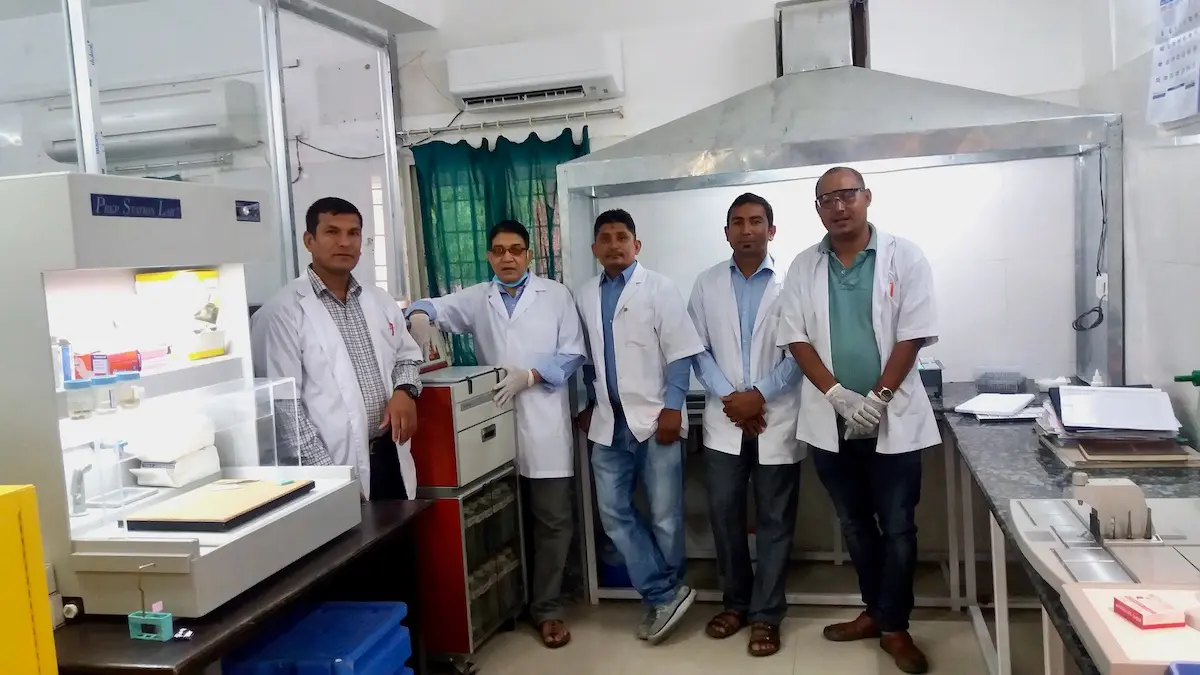 Five Nepalese men in laboratory coats stand inside the new histology lab at Lalgadh Leprosy Hospital in Nepal.