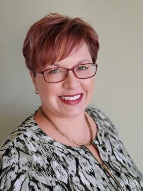 Headshot of Leeann Parker, white woman with short auburn hair and glasses