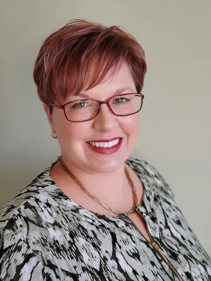 Headshot of Leeann Parker, white woman with short auburn hair and glasses
