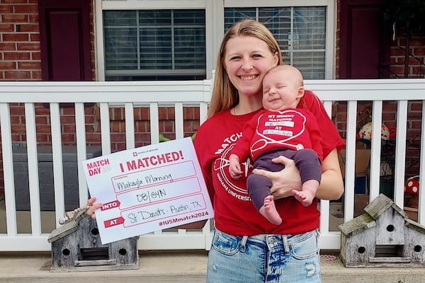 Makayla Morning holding her baby and a Match Day sign