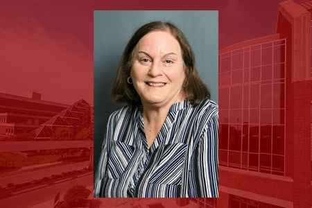 Headshot of Marlyn Baker wearing striped blouse on red campus building background
