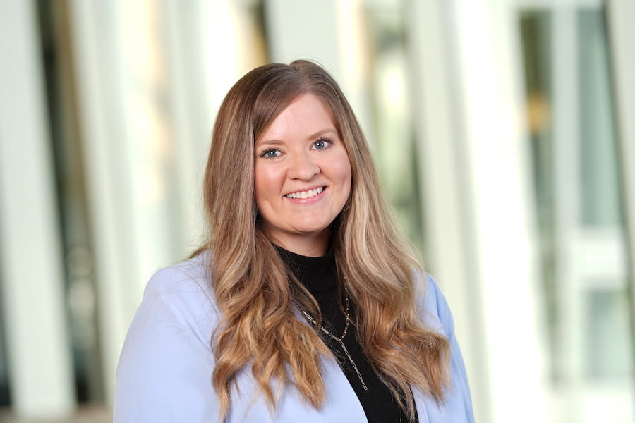 Head and shoulders shot of Courtney Medlock, woman with long hair wearing black blouse and lavender blazer