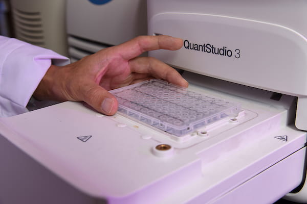 Closeup of machine for scientific research with person's hand adjusting samples