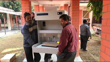 Two men carry laboratory equipment for a histology lab in Nepal.