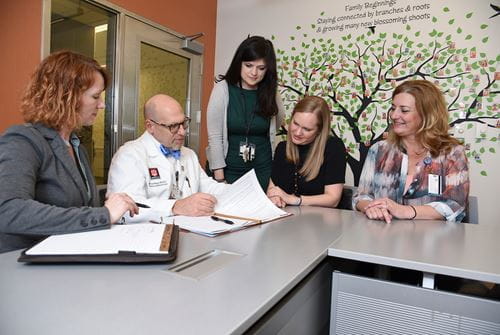 Dr. Peipert sits at a table with four women researchers going over papers
