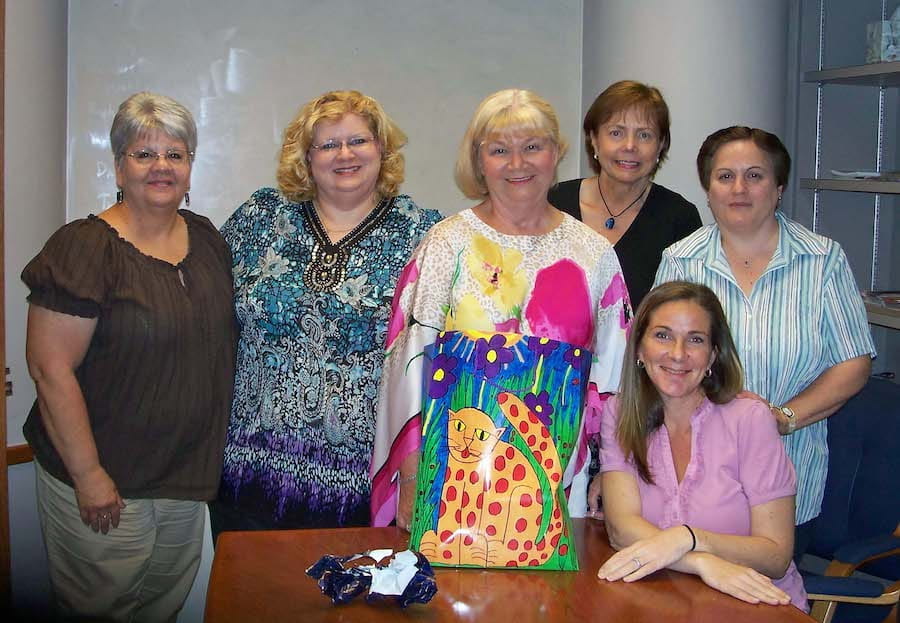 Six women, including Marilyn Baker, from the Pediatrics office staff gather around a table in 2011. 