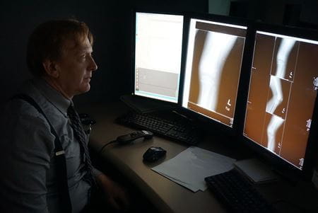 Dr. Richard Gunderman in dark room looking at leg scans on computer screens