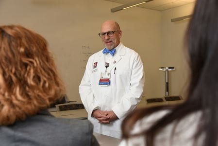 Dr. Peipert, wearing white coat, talks to learners in a classroom