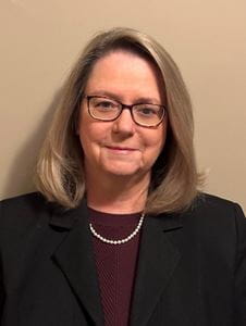 Headshot of Angie Rinehart, white woman with blonde hair and glasses in professional attire