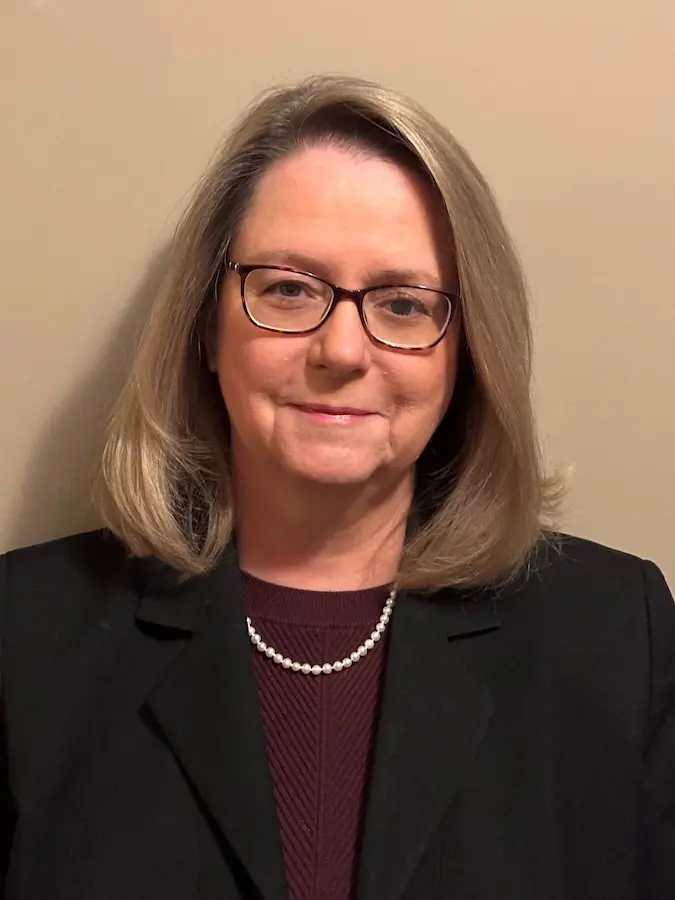 Headshot of Angie Rinehart, white woman with blonde hair and glasses in professional attire
