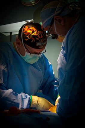 Dr. Ritter performs a surgery wearing surgical scrubs and a Harley Davidson skullcap