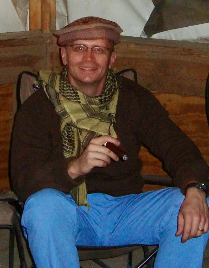 Dr. Ritter smoking a cigar as he sits on the hospital roof, wearing a cap and scarf