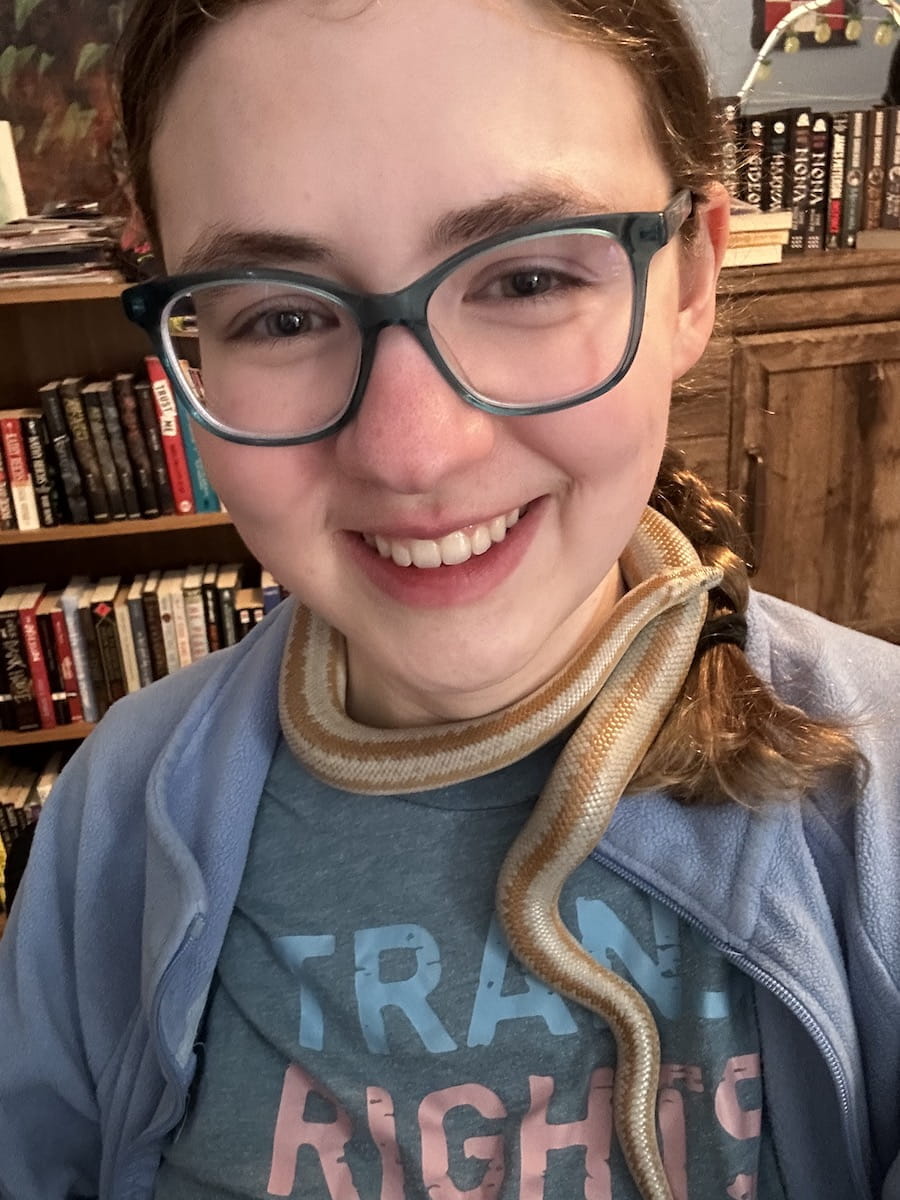 Sarah Vaught, smiling with her pet rosy boa wrapped around her neck