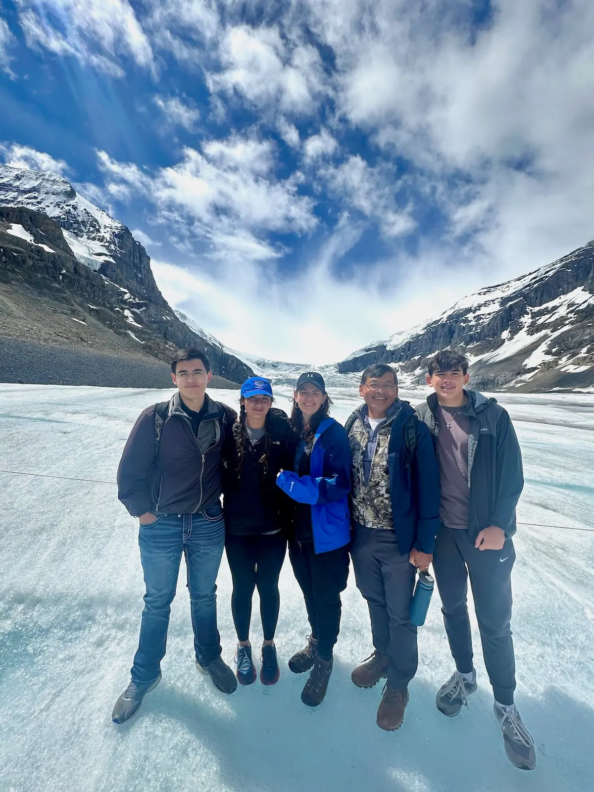 Michele and Chan Saysana with their three young adult children standing outside near snow-covered mountains