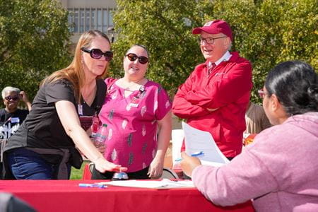 Dean Jay Hess, in red hat, standing by IUSM staff playing a game
