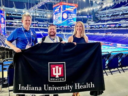 IU Health providers Steve Hartsock, Damon Martin and Kimbre Zahn lead the USA Swimming medical team for the Olympic Trials at Lucas Oil Stadium. Steve Hartsock, Damon Martin and Kimbre Zahn hold an Indiana University Health banner near the pool deck at Lucas Oil Stadium